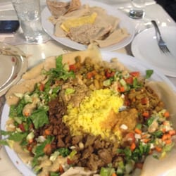 Afro-Canadian Restaurant - Vancouver, BC, Canada. The meat platter with lamb,  beef and chicken items,  salad and two vegetarian dishes and rice placed on  sour crepe like injera