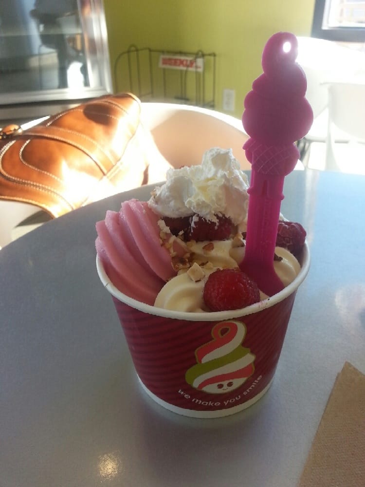 A mixture of pomegranate , bannana yogurt with raspberries, almonds and