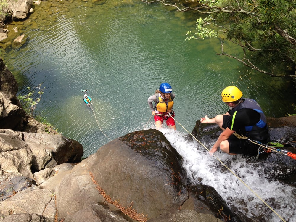 Rappel Maui guide helping a rappeller go down next to a waterfall