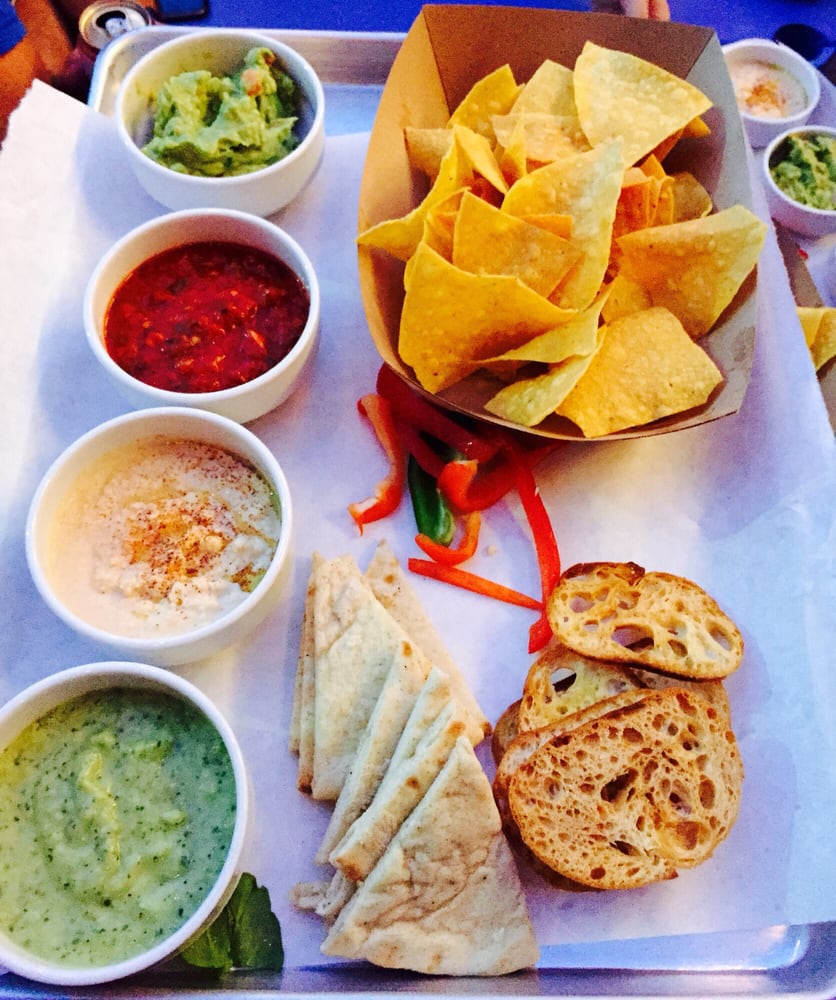 Incredible dip board with hummus, green and red salsa, guac served with